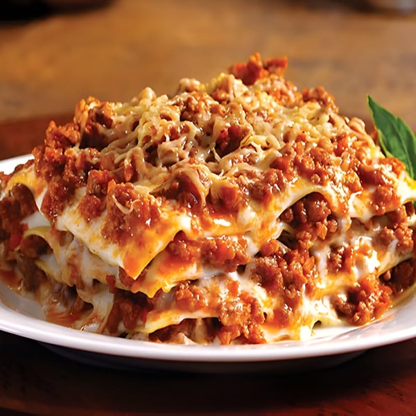 A generous serving of lasagna with rich meat sauce and melted cheese on a white plate.