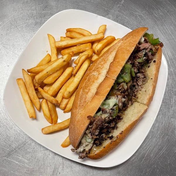 A Juniors Pizza and more cheesesteak with green peppers and onions, served with a side of fries.