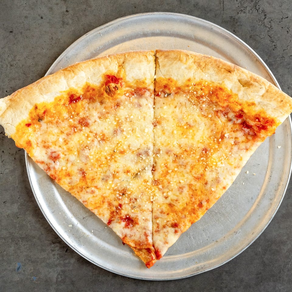 Two large slices of cheese pizza with red sauce and parmesan on a metal tray.